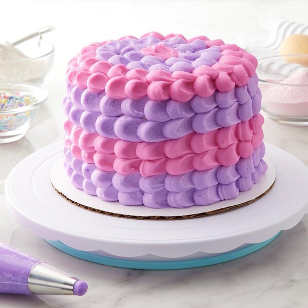cake with pink and purple icing next to pastry bag